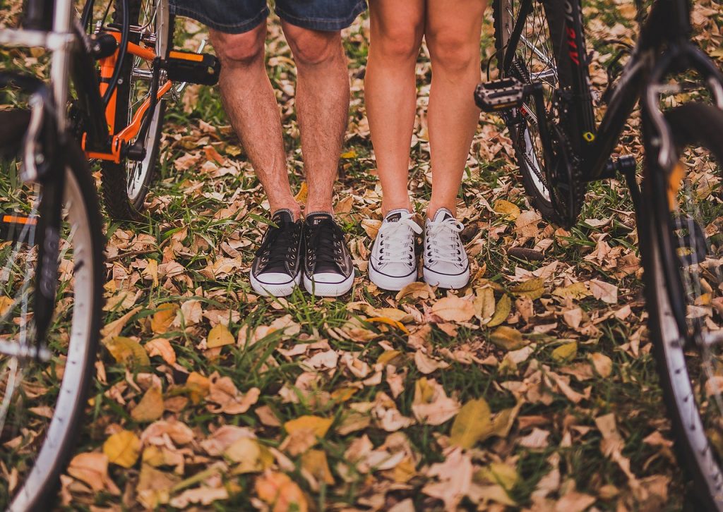 vue sur le bas des jambes d'un homme et d'une femme portant des baskets à côté de vélos